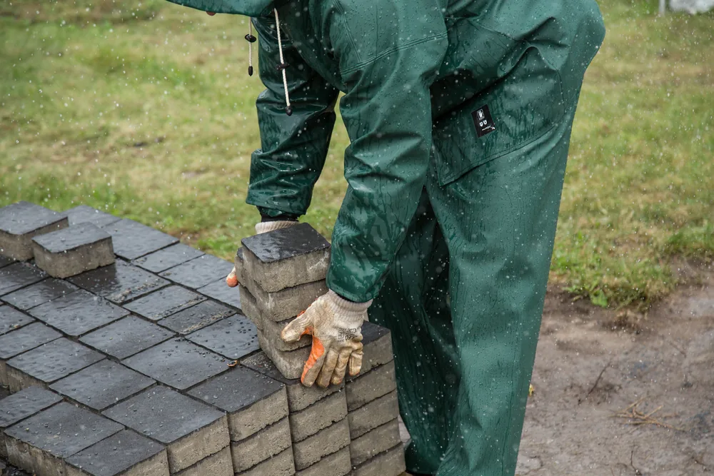 A mason setting paving stones by hand