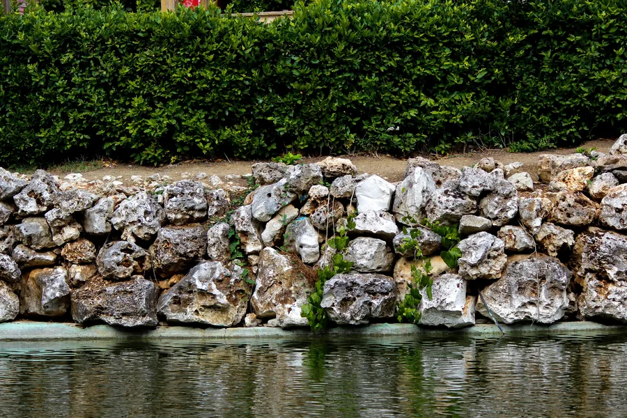 A dry-stacked stone retaining wall beside water